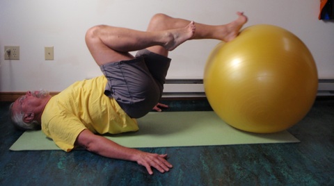 Coach John Hughes demonstrating ball single leg hamstring curl exercise for core strength training for cyclists